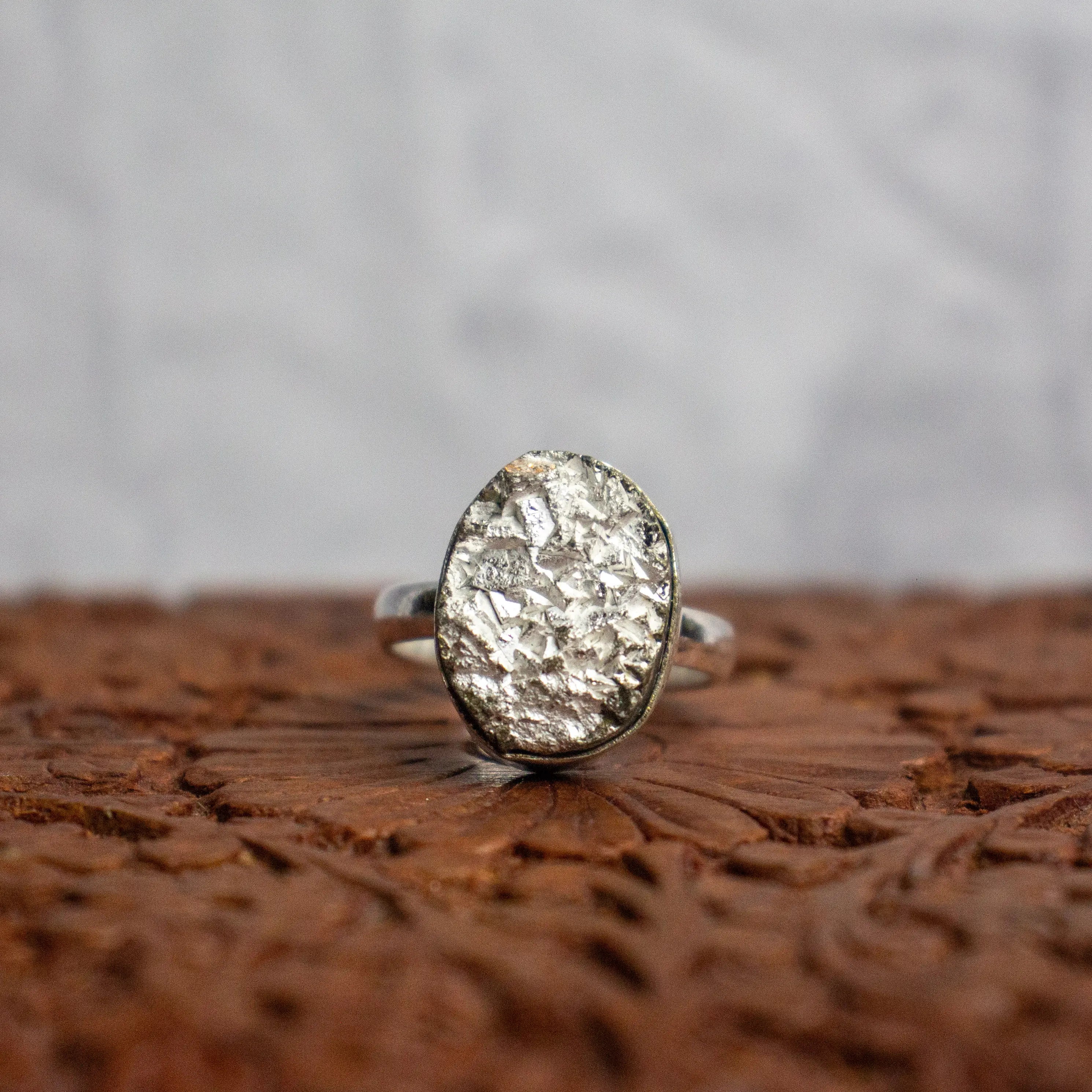 Silver ring with textured design on a wooden surface