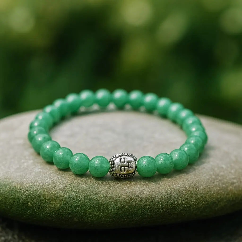 Green beaded bracelet with a silver charm on a stone surface with a blurred green background